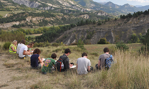 A group of students looking out and taking notes while on a field trip