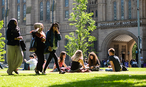 Students sat on the grass on camous during an open day